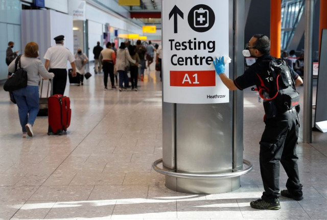a worker sanitises a sign at the international arrivals area of terminal 5 in london s heathrow airport britain august 2 2021 photo reuters a worker sanitises a sign at the international arrivals area of terminal 5 in london s heathrow airport britain august 2 2021 photo reuters