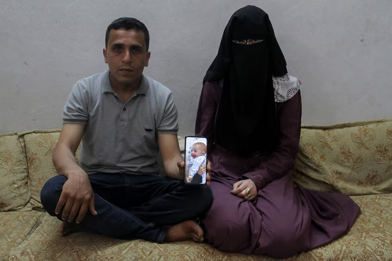 Zakaria Hamuda and his wife Sondos, parents of Palestinian infant Yehia, who was evacuated to south Gaza as a premature baby after Israeli forces raided Kamal Adwan hospital in northern Gaza Strip and is currently separated from his parents due to an Israeli checkpoint that separates north Gaza from the south, display a picture of him on a mobile phone, in Jabalia in the northern Gaza Strip, April 25, 2024. PHOTO: REUTERS