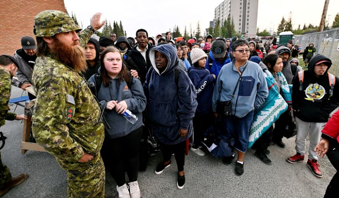 hundreds of people line up outside a local high school waiting to be taken to the airport for one of the five evacuation flights planned photo reuters screengrab