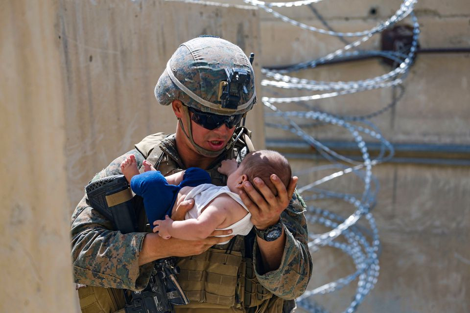 A U.S. Marine comforts an infant while they wait for the mother during an evacuation at Hamid Karzai International Airport, Afghanistan, August 21, 2021. Picture taken August 21, 2021. U.S. Marine Corps/Lance Cpl. Nicholas Guevara/Handout via REUTERS