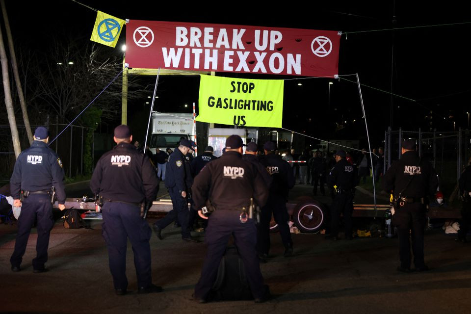officers from the new york city police department nypd watch on as activists from extinction rebellion take part in an earth day demonstration blockading the gate of the new york times distribution print facility in queens new york city u s april 22 2022 reuters andrew kelly