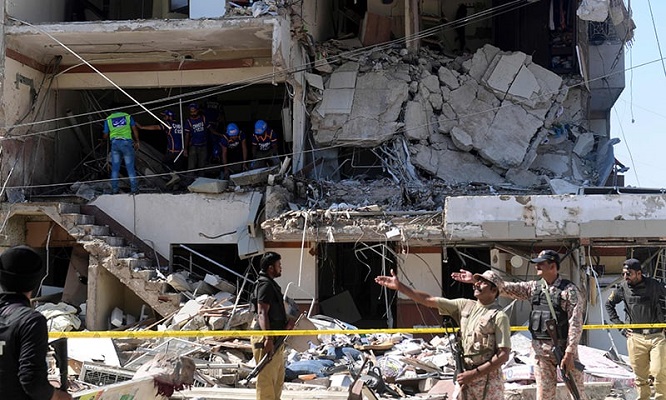 Security and rescue officials stand amid the damaged structure. Photo: AFP