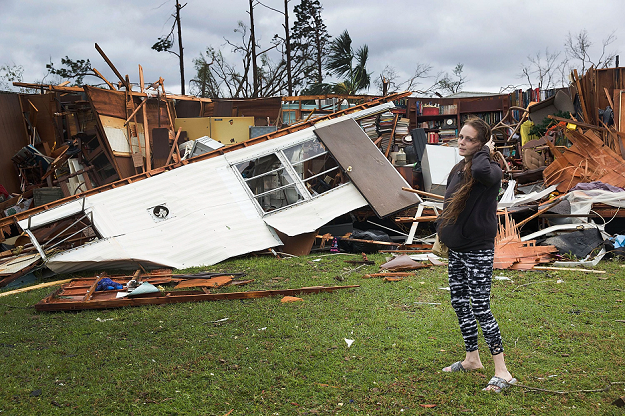 A woman stands in front of the remains of her father's motor home. PHOTO AFP