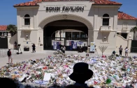 mourners stand near tributes piled together at the front of the bondi pavilion in memory of the victims of the bondi beach shooting in sydney on december 17 2025 photo afp