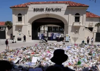 mourners stand near tributes piled together at the front of the bondi pavilion in memory of the victims of the bondi beach shooting in sydney on december 17 2025 photo afp