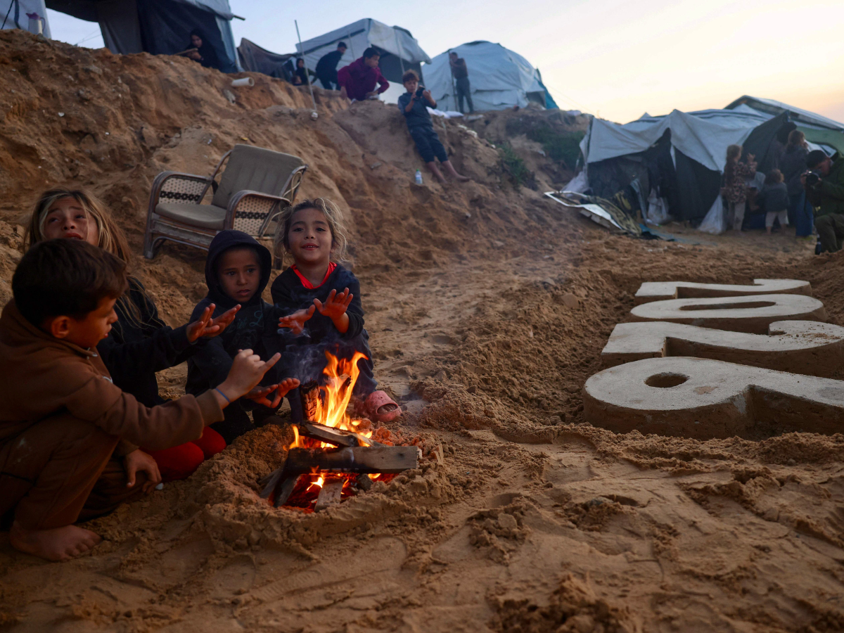 Children warm by the fire next to a sand sculpture by artist Yazed Abo Jarad of the coming year as Displaced Palestinians prepare to usher in the New Year in Deir El-Balah in the central Gaza Strip on December 30, 2025. Beginning in October, a fragile ceasefire has so far halted two years of war between Israel and Hamas in the Gaza Strip despite both sides trading accusations of truce violations. Photo: AFP
