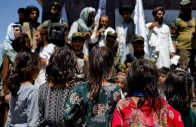 afghan girls look at taliban supporters on the second anniversary of the fall of kabul on a street near the us embassy in kabul afghanistan august 15 2023 reuters