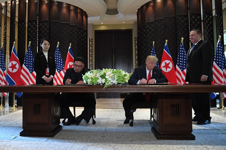 us president donald trump 2nd r and north korea s leader kim jong un 2nd l sign documents as us secretary of state mike pompeo r and the north korean leader s sister kim yo jong l look on at a signing ceremony during their historic us north korea summit at the capella hotel on sentosa island in singapore on june 12 2018 photo afp