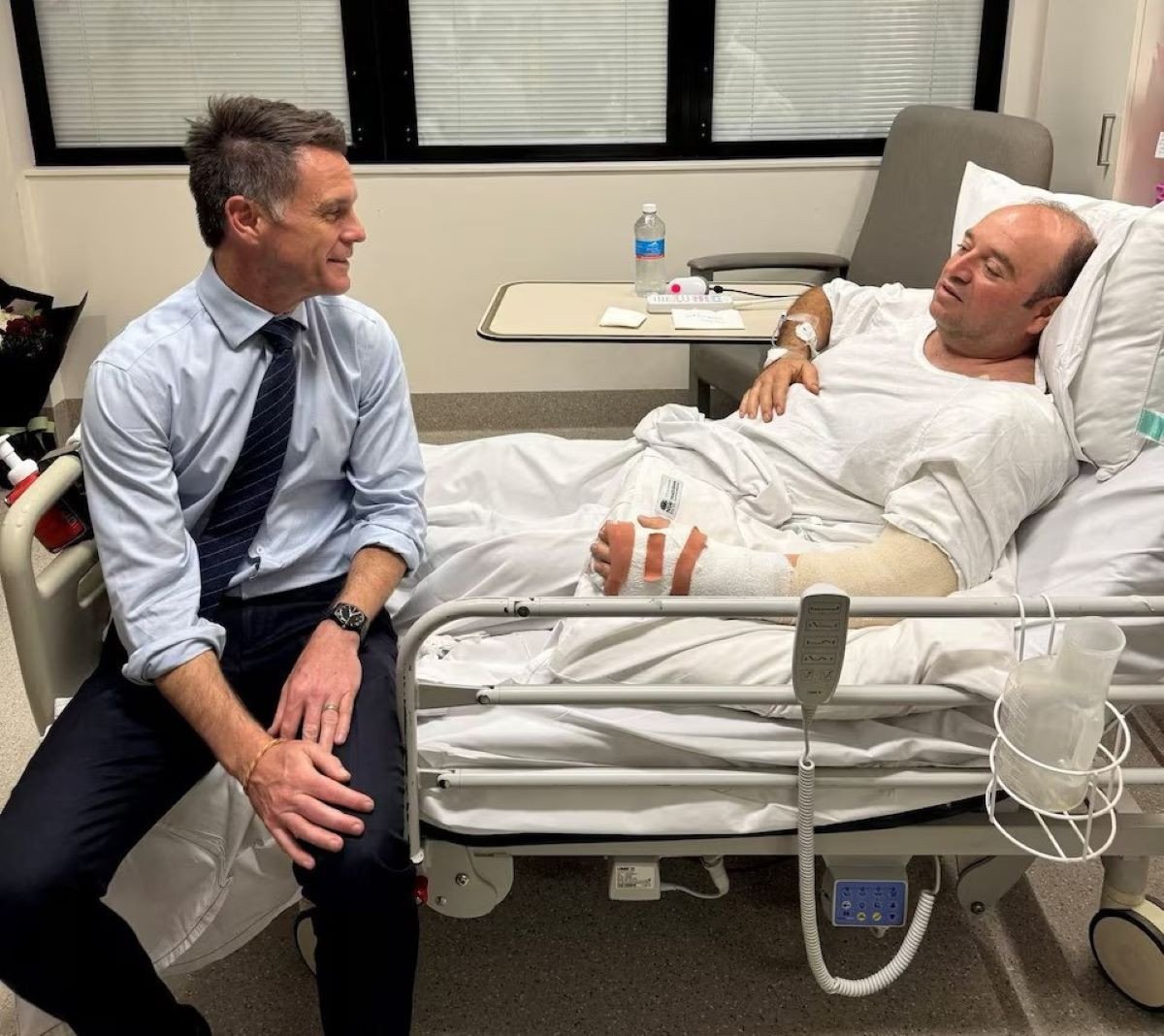 نیو ساؤتھ ویلز کے پریمیئر کرس منز نے احمد الحم کا دورہ کیا ، جن کی شناخت سوشل میڈیا پر کی گئی تھی ، جس نے بائی اسٹینڈر کے طور پر کھڑی کاروں کے پیچھے چھپایا تھا اور اتوار کے روز ، بونڈی بیچ میں ایک بندوق برداروں سے ایک رائفل پکڑی تھی ، سڈنی ، آسٹریلیا ، 15 دسمبر ، 2025 میں ، سوشل میڈیا سے حاصل کی گئی اس تصویر میں۔ @chrisminnsmp کے ذریعے X/رائٹرز کے ذریعے