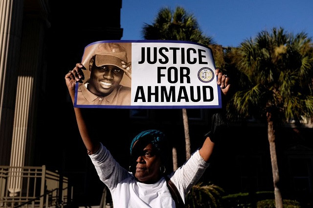 a woman holds a sign outside the glynn county courthouse after the jury reached a guilty verdict in the trial of william roddie bryan travis mcmichael and gregory mcmichael charged with the february 2020 death of 25 year old ahmaud arbery in brunswick georgia u s november 24 2021 reuters marco bello