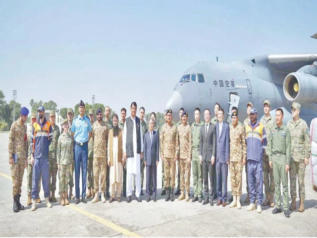 pakistani and chinese officials pose in front of one of the two chinese aircraft that arrived at nur khan base in rawalpindi with relief goods photo app
