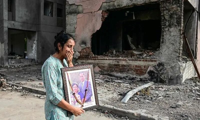 A woman holding a portrait of her relatives, who died in the Air India Flight 171 crash last year, breaks down while visiting the accident site in Ahmedabad on June 11. PHOTO: AFP