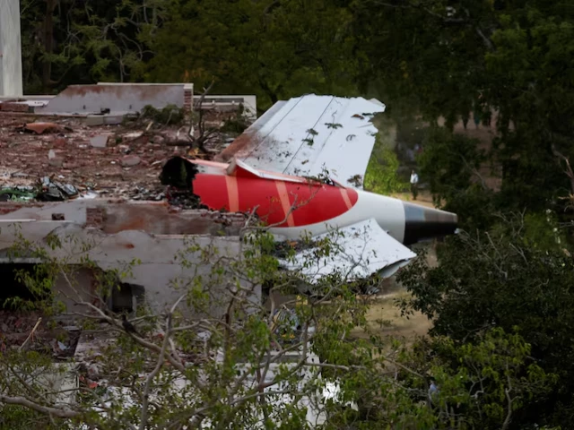 a tail of an air india boeing 787 dreamliner plane that crashed is seen stuck on a building after the incident in ahmedabad india