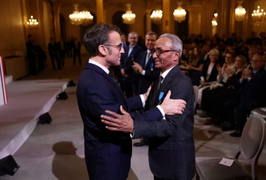 french president emmanuel macron l wearing sunglasses awards the chevalier of the french order of merit to ali akbar who hawks newspapers around the streets of saint germain des pres in the french capital for 50 years at the elysee palace in paris on january 28 2026 photo afp