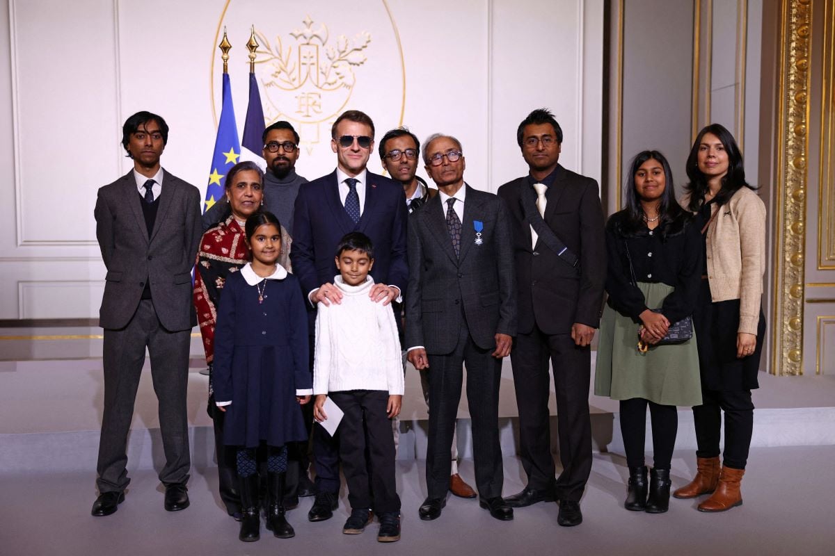 French President Emmanuel Macron (C-L), wearing sunglasses, poses with Akbar and his relatives after awarding the Chevalier of the French Order of Merit to Ali Akbar, who hawks newspapers around the streets of Saint-Germain-des-Pres in the French capital for 50 years, at the Elysee Palace in Paris on January 28, 2026.AFP