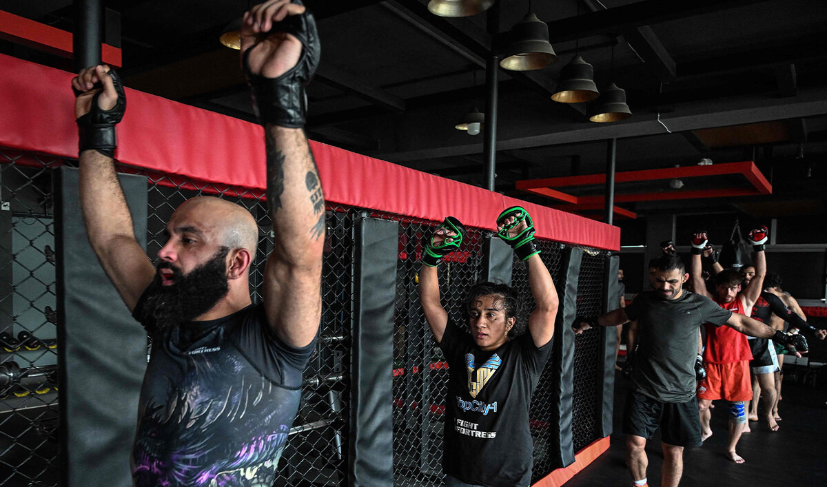 In this photograph taken on December 11, 2024, Anita Karim (2L), a mixed martial arts (MMA) fighter, warms up with her brother and coach Uloomi (L) before a training session at a club in Islamabad. (AFP/File)