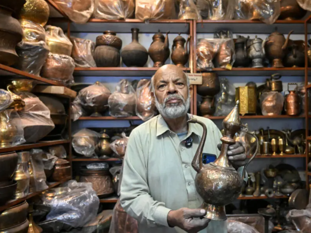 Antique dealer Ahsan Shakeel shows an artefact at his shop selling vintage items in Rawalpindi. PHOTO: AFP