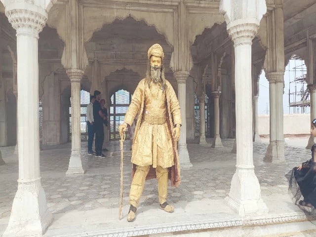 an artiste donning golden attire and painted hands and face performs as a statue inside shahi qila photo express an artiste donning golden attire and painted hands and face performs as a statue inside shahi qila photo express