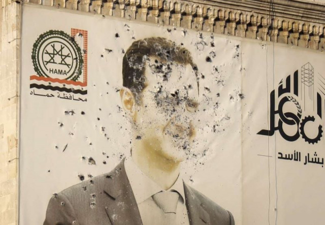 this aerial picture shows a bullet riddled portrait of syrian president bashar al assad adorning hama s municipality building after it was defaced following the capture of the city by anti government fighters on december 6 photo afp this aerial picture shows a bullet riddled portrait of syrian president bashar al assad adorning hama s municipality building after it was defaced following the capture of the city by anti government fighters on december 6 photo afp