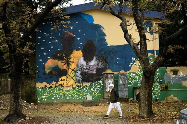 A man walks past a mural depicting women whose faces and hands were blackened by extremists ahead of a planned women march. PHOTO: AFP