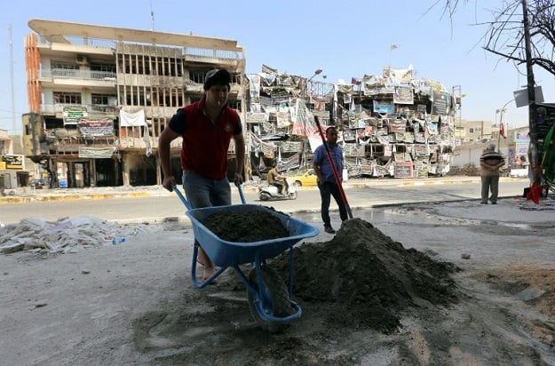 Iraqi workers rebuild on July 31, 2016 a shop that was damaged in a bombing in Baghdad's Karrada Dakhil street in the capital's commercial Karrada district. PHOTO: AFP