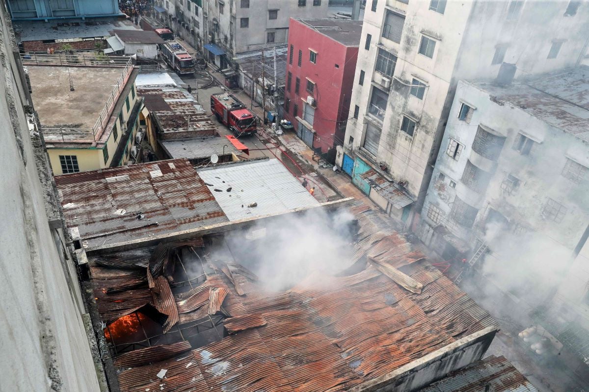 Firefighters douse flames as smoke rises from the burning chemical and garments factory in Dhaka.PHOTO:AFP