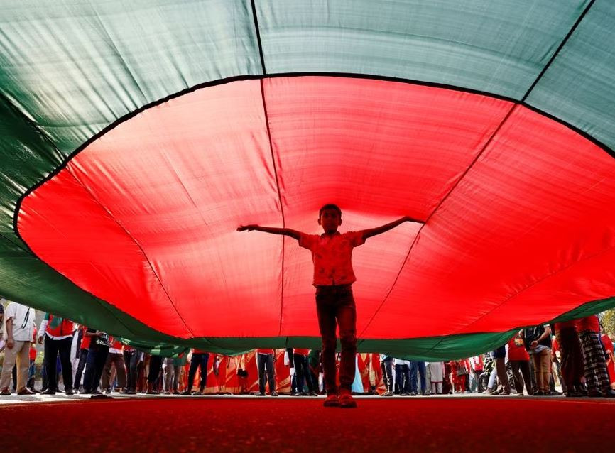 a boy poses for a picture under a massive bangladeshi flag during a flag rally three days ahead of the country s 50th victory day anniversary in front of the parliamentary building in dhaka bangladesh december 13 2021 photo reuters file