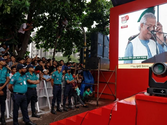 people watch muhammad yunus leader of bangladeshi interim government as he appears on a screen while reading the july declaration during celebrations marking the one year anniversary of student led protests that led to the ousting of bangladeshi then prime minister sheikh hasina at manik mia avenue outside the parliament building in dhaka bangladesh august 5 2025 photo reuters people watch muhammad yunus leader of bangladeshi interim government as he appears on a screen while reading the july declaration during celebrations marking the one year anniversary of student led protests that led to the ousting of bangladeshi then prime minister sheikh hasina at manik mia avenue outside the parliament building in dhaka bangladesh august 5 2025 photo reuters