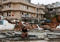 a person sits beside a collapsed wall in the aftermath of typhoon bavi in the coastal village of dongsha taizhou zhejiang province china july 12 2026 photo reuters