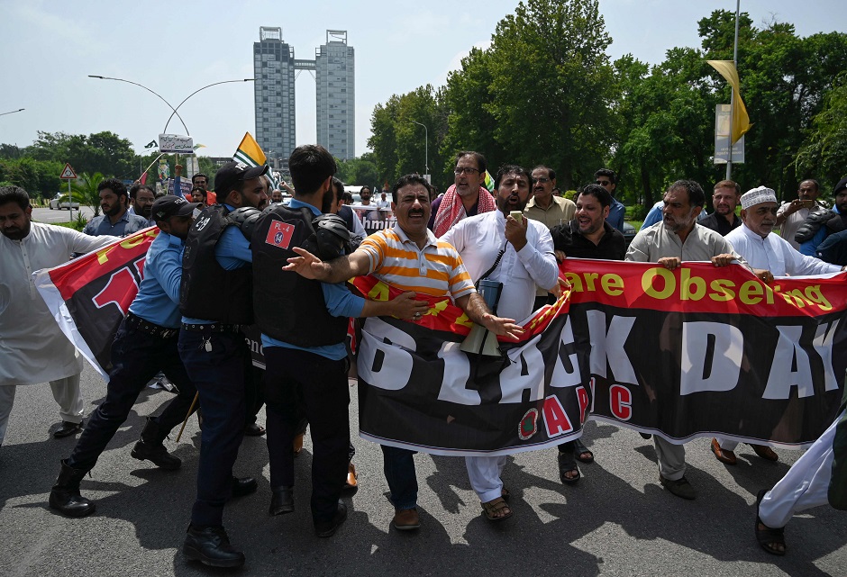 Riot policemen try to stop Kashmiri protesters of the All Parties Hurriyat Conference (APHC) during a protest rally near the Indian High Commission in Islamabad. PHOTO: AFP