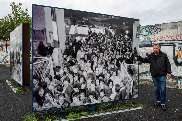 Andreas Falge, one of thousands of east Germans who crossed into west Berlin through the Bornholmer Strasse checkpoint on the evening of November 9, 1989, poses next to a photograph taken that very evening, which forms part of a memorial near the Boesebruecke (Boese bridge) which straddled the border (Photo: AFP)