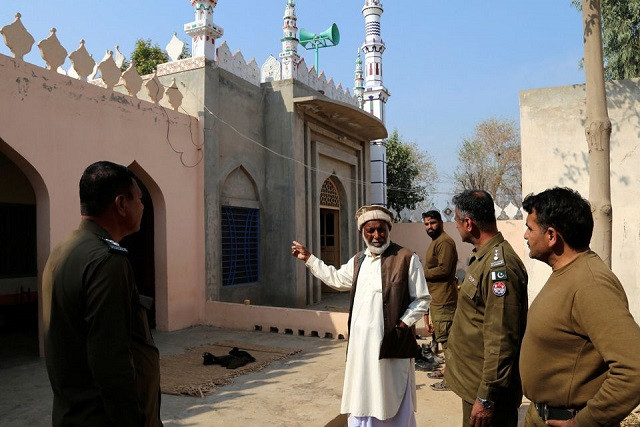 a villager speaks with police officers at a mosque after according to the police a mob lynched a man for allegedly burning pages of holy quran in tulamba village in mian channu on february 13 2022 reuters arshad raza zaidi