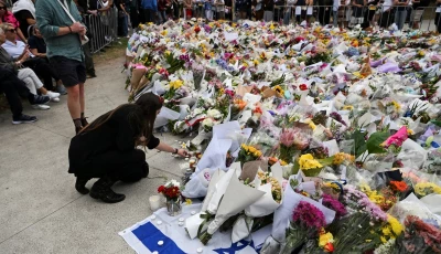 a woman keeps a candle next to flowers laid as a tribute at bondi beach to honour the victims of a mass shooting that targeted a hanukkah celebration at bondi beach on sunday in sydney australia december 16 2025 photo reuters