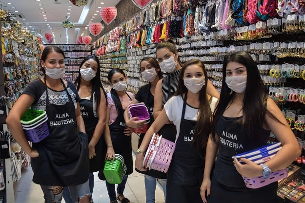 Shop sellers pose as they wear face masks as a preventive measure against the spread of the new coronavirus. PHOTO: AFP