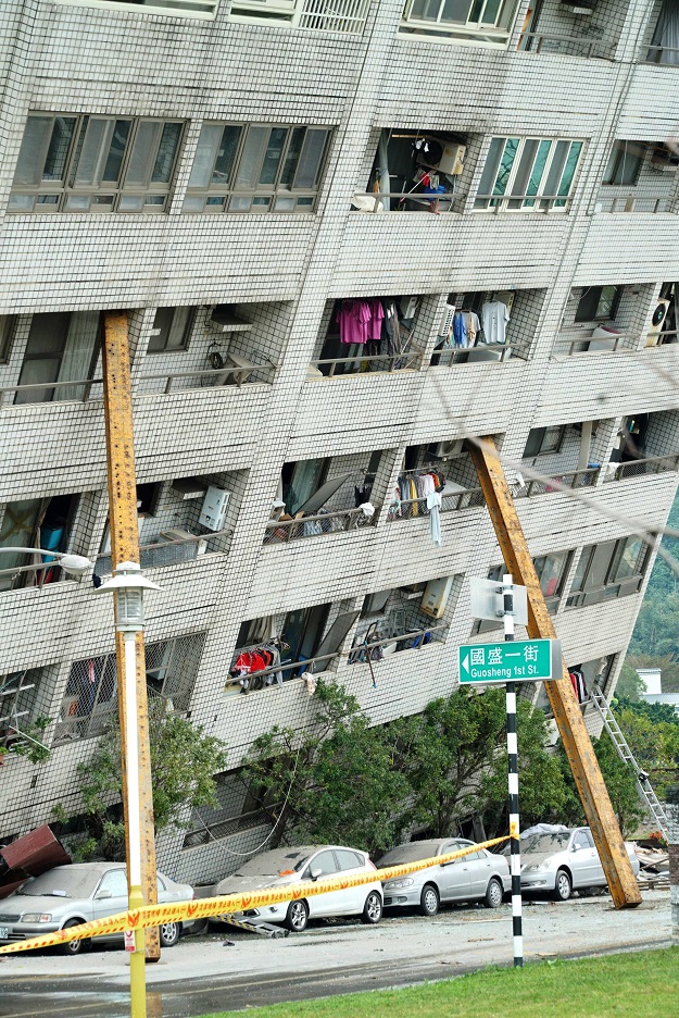 Rescue and emergency workers block off a street where a building came off its foundation, the morning after a 6.4 magnitude quake hit the eastern Taiwanese city of Hualien, on February 7, 2018. Rescue workers scrambled to search for survivors in buildings left tilting precariously on their foundations in the Taiwanese city of Hualien on February 7, after an overnight earthquake killed four and injured more than 200. PHOTO:AFP