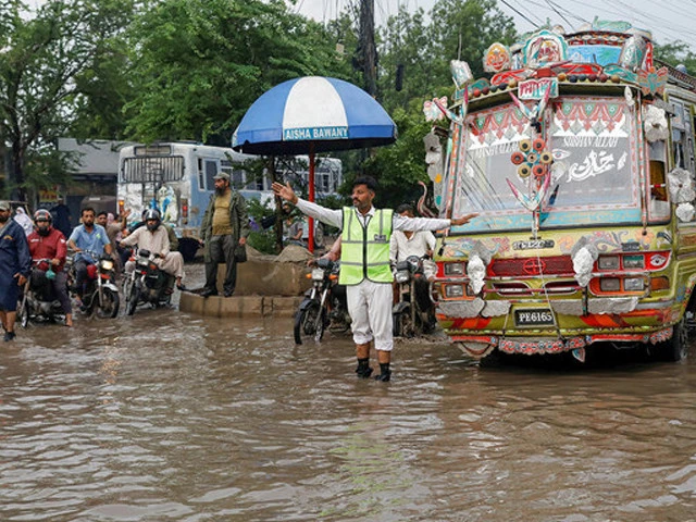 police officer controls traffic while standing amid rain waters in karachi on august 10 2022 photo reuters