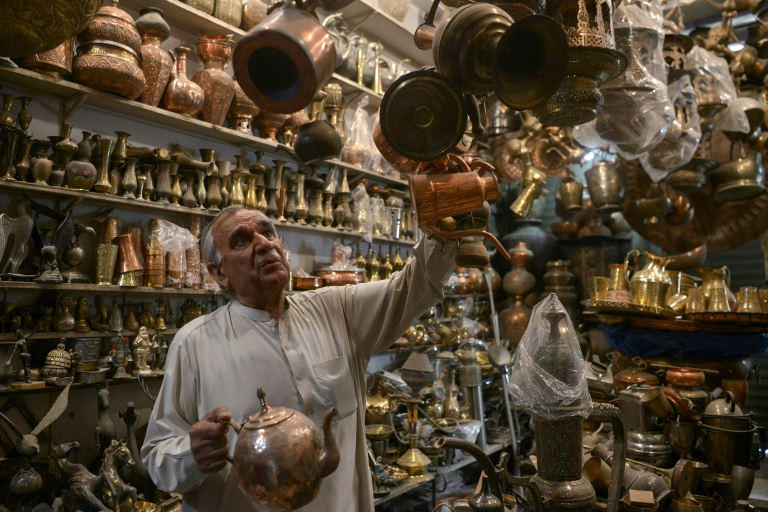 khwaja safar ali 75 arranges items in his antiques shop at the oldest qissa khawani or storytellers bazaar in pakistan s northwestern city of peshawar afp