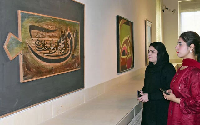 visitors look at a painting of quranic ayat during an art exhibition at the pakistan national council of the arts pnca in islamabad on march 14 2024 photo online