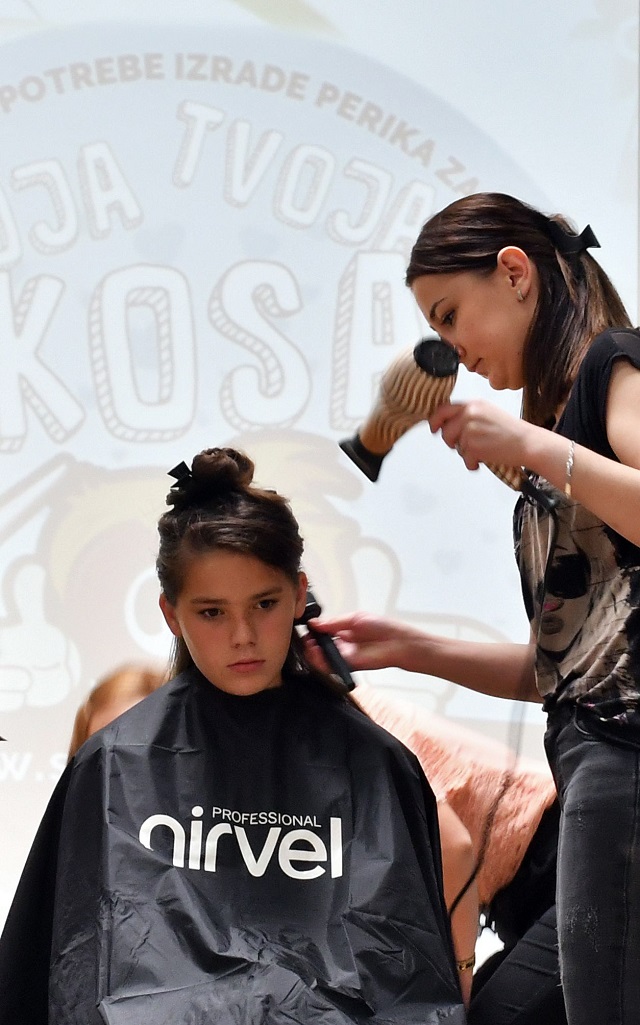 A hairdresser prepares the hair of a young donor before snipping off some as part of the "My Hair Your Hair" campaign in Sarajevo on May 25, 2018. PHOTO: AFP