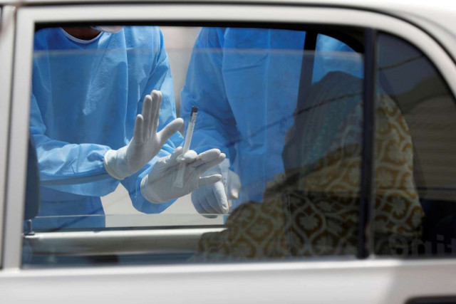 a health worker collects swab from a woman in a car photo reuters a health worker collects swab from a woman in a car photo reuters