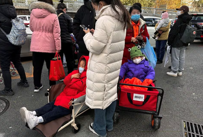 people stand next to children sitting in camping carts as they wait for their rides outside a children s hospital in beijing china november 27 2023 reuters tingshu wang file photo acquire licensing rights