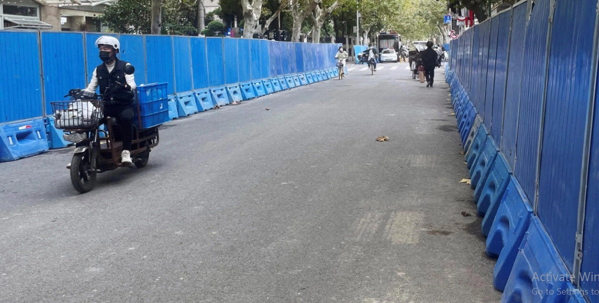 people ride past barriers set up along a road where protests against covid 19 curbs took place following the deadly urumqi fire in shanghai china november 28 2022 casey hall reuters