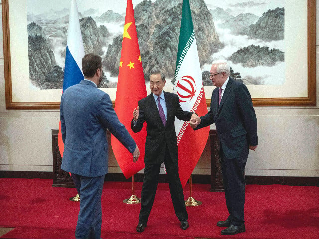 china s foreign minister wang yi c gestures as he welcomes russia s deputy foreign minister sergey ryabkov r and iran s deputy foreign minister kazeem gharibabadi in beijing photo afp