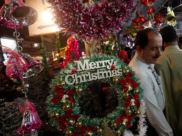 people walk past a decoration wreath hanging outside a shop selling various items for christmas celebrations in karachi pakistan photo reuters people walk past a decoration wreath hanging outside a shop selling various items for christmas celebrations in karachi pakistan photo reuters