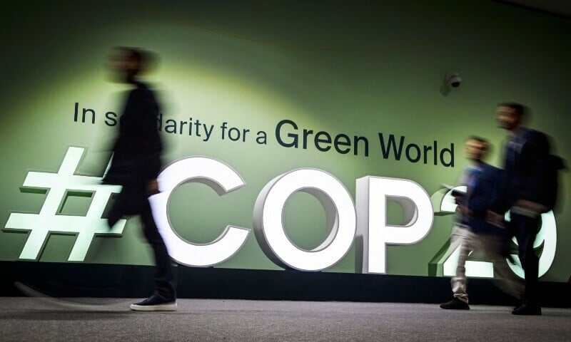 people walk past the logotype at the venue for the 2024 united nations climate change conference cop29 in baku on nov 11 2024 photo afp