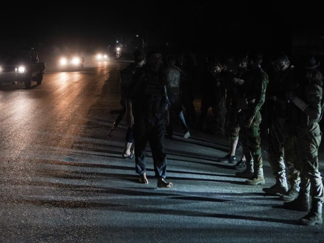 Members of Syrian security forces stand on the side of a road in Sweida countryside, as vehicles transporting other Syrian security forces make their way out of the predominantly druze city of Sweida, Syria, July 16, 2025. REUTERS/Karam al-Masr