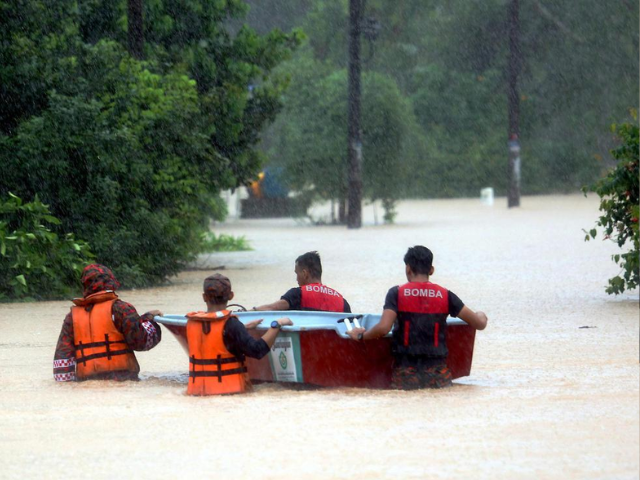 fire and rescue department personnel wading through flood waters to evacuate flood victims in kampung pasir tebrau johor baru photo the star asia news network