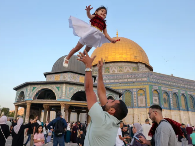 A father celebrates with a child at the Al-Aqsa Mosque compound in occupied Jerusalem [Ahmad Gharabli/AFP]