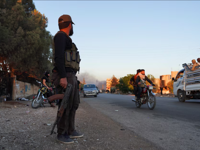 A Bedouin fighter holds a weapon as he stands along a street, as Sweida province has been engulfed by nearly a week of violence triggered by clashes between Bedouin fighters and factions from the Druze, at Sweida governorate, Syria, July 18, 2025. REUTERS/Karam al-Masri