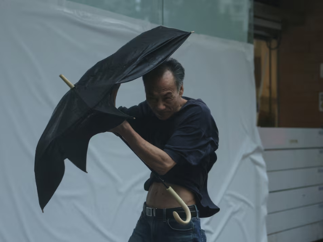 A man struggles with an umbrella while walking against strong wind, as Typhoon Wipha approaches, in Hong Kong, China, July 20, 2025. REUTERS/Tyrone Siu